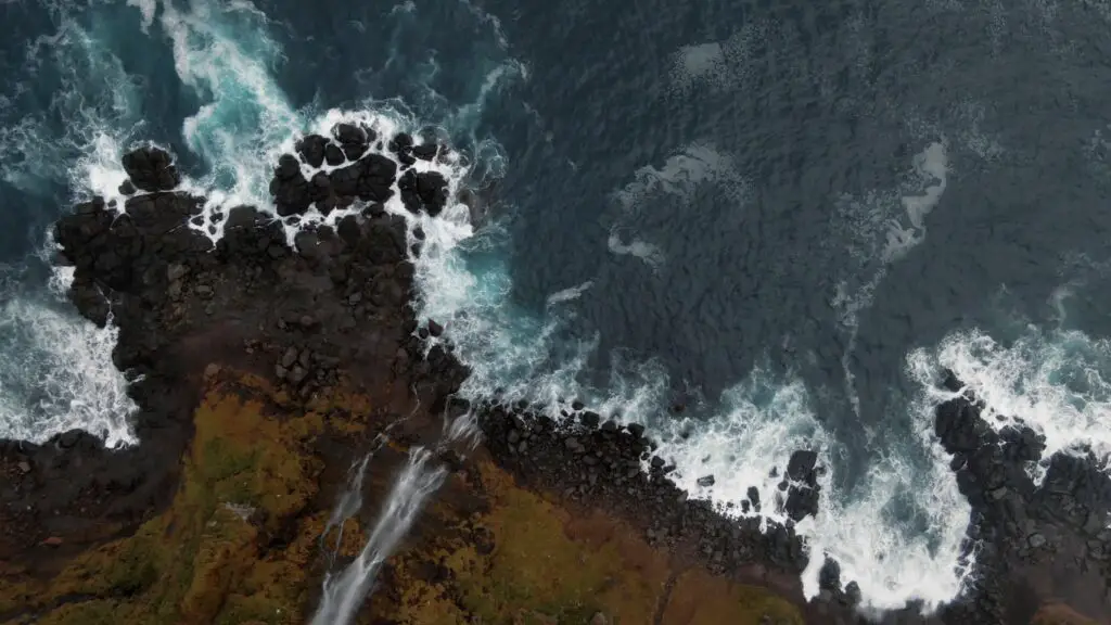 Top-down aerial view of a volcanic cliff over the ocean in Iceland