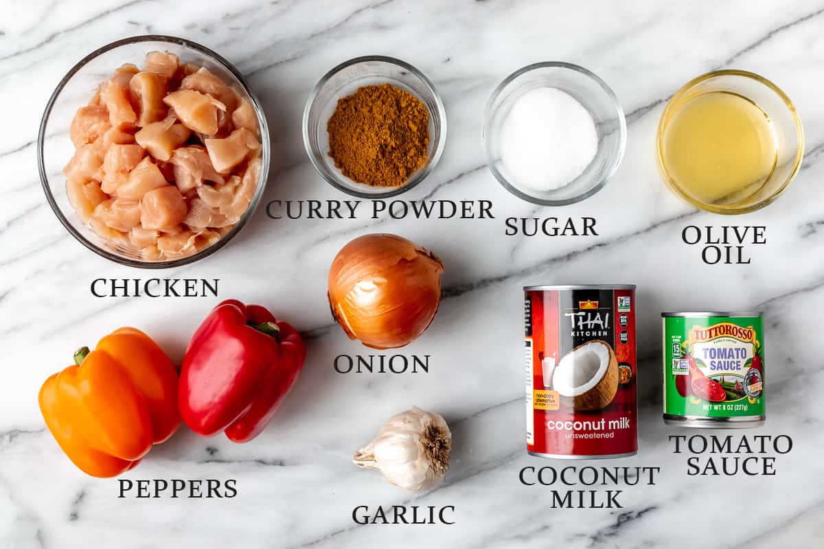 Ingredients needed to make coconut curry chicken on a marble background with text overlay.
