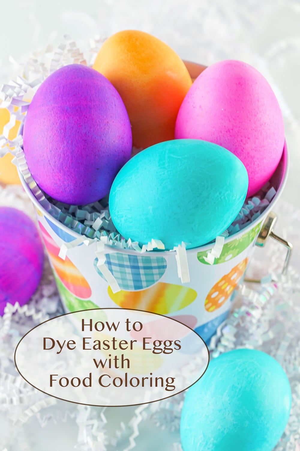 dyed Easter eggs in an Easter pail with white Easter grass around.