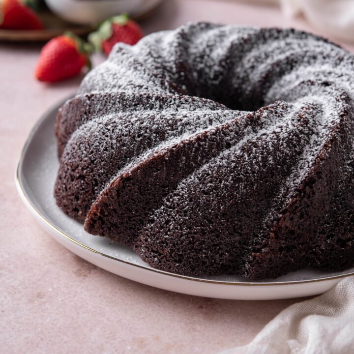 A sugar dusted chocolate pound cake sits on a white serving platter.