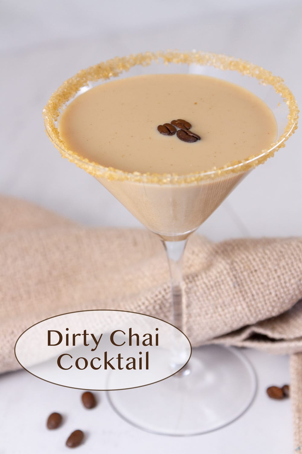 a martini glass with a chai cocktail with 3 coffee beans floating on top and a sugared rim.