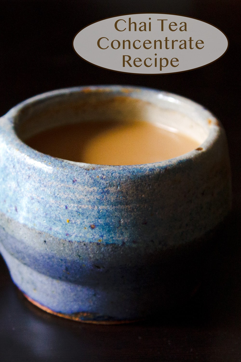 a blue mug filled with chai tea on a black background.