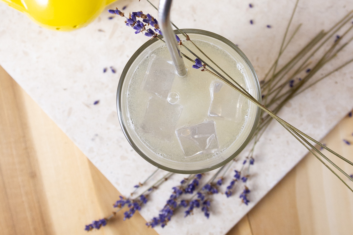 looking down into a glass of lavender lemonade with lavender sprigs around.