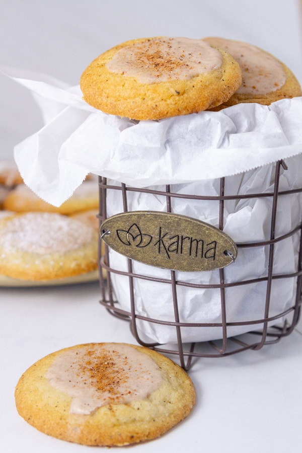 a wire basket with parchment paper and cookies in in with a cookie next to the basket.