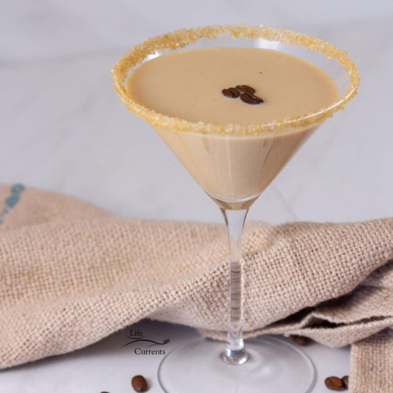 square crop of a martini glass filled with chai drink with coffee beans floating on top, a sugared rim, and a cloth napkin behind it.